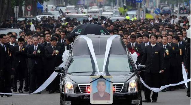 喧嚣过后,一辆灵车缓缓驶出,灵车前面挂着一张照片,照片中的人面容