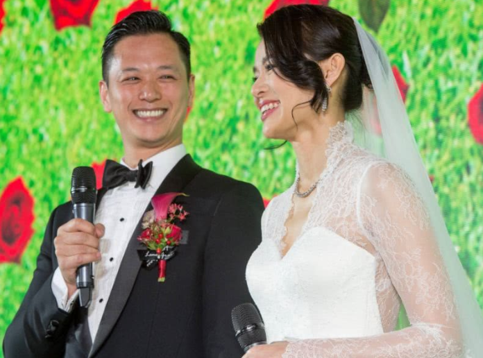 大儿子李奕霆在镜头前微笑,看起来很害羞,他双手撑着伞为弟弟撑着伞