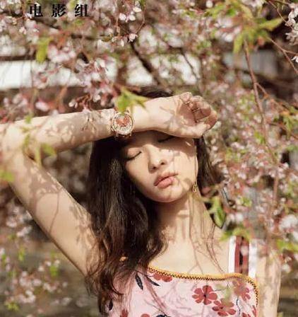 图中,她穿着校服,披散着头发,站在花树下