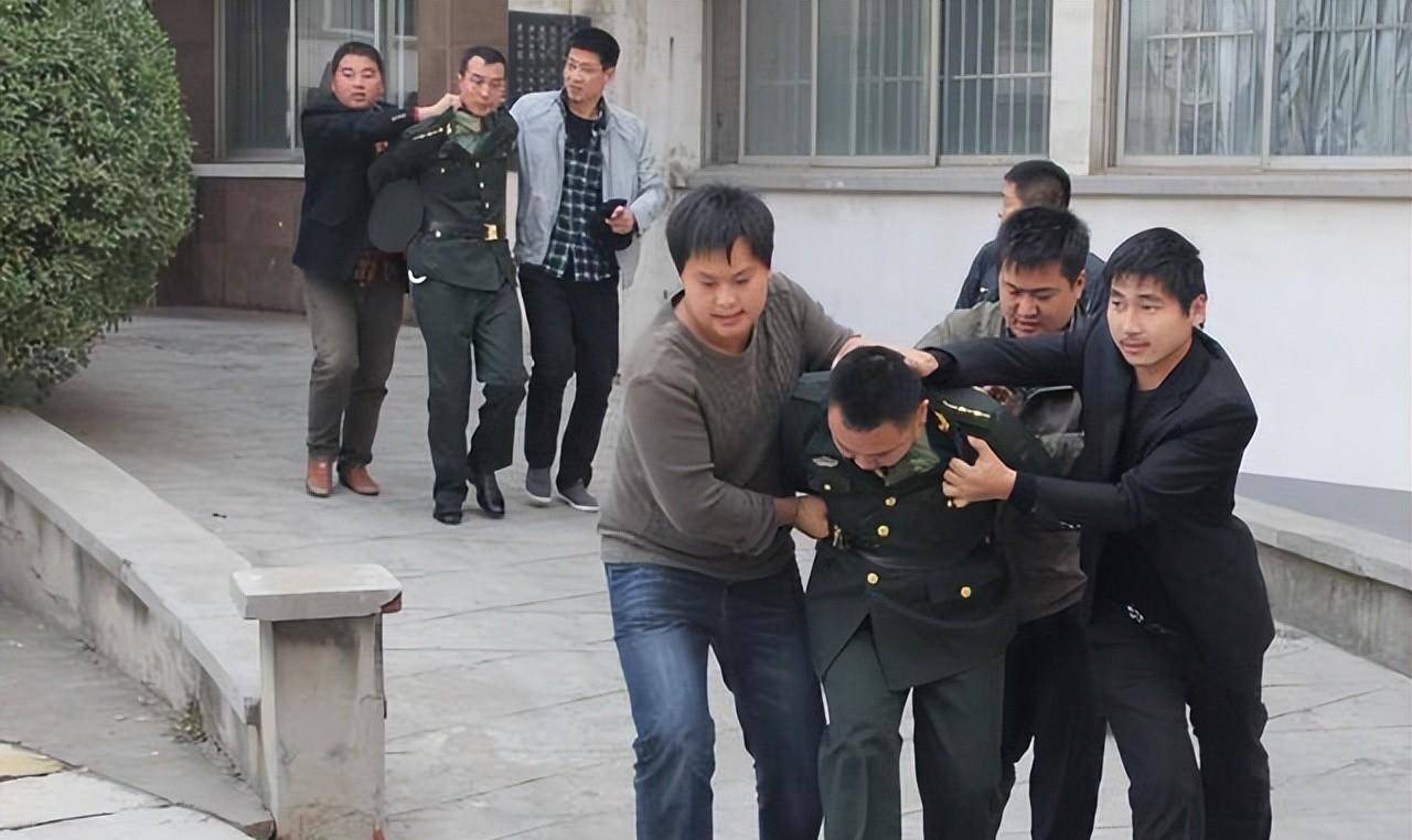 2013年,北京某小区,一名穿着军装的男子被便衣警察押了出来,他不断地
