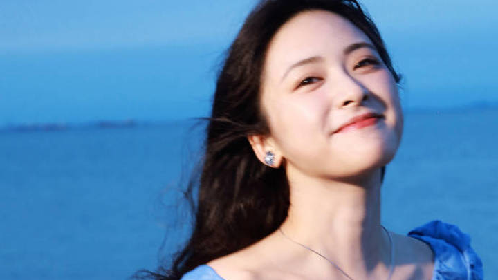 沈月穿蓝色连衣裙海边拍照，她笑容甜美吗？