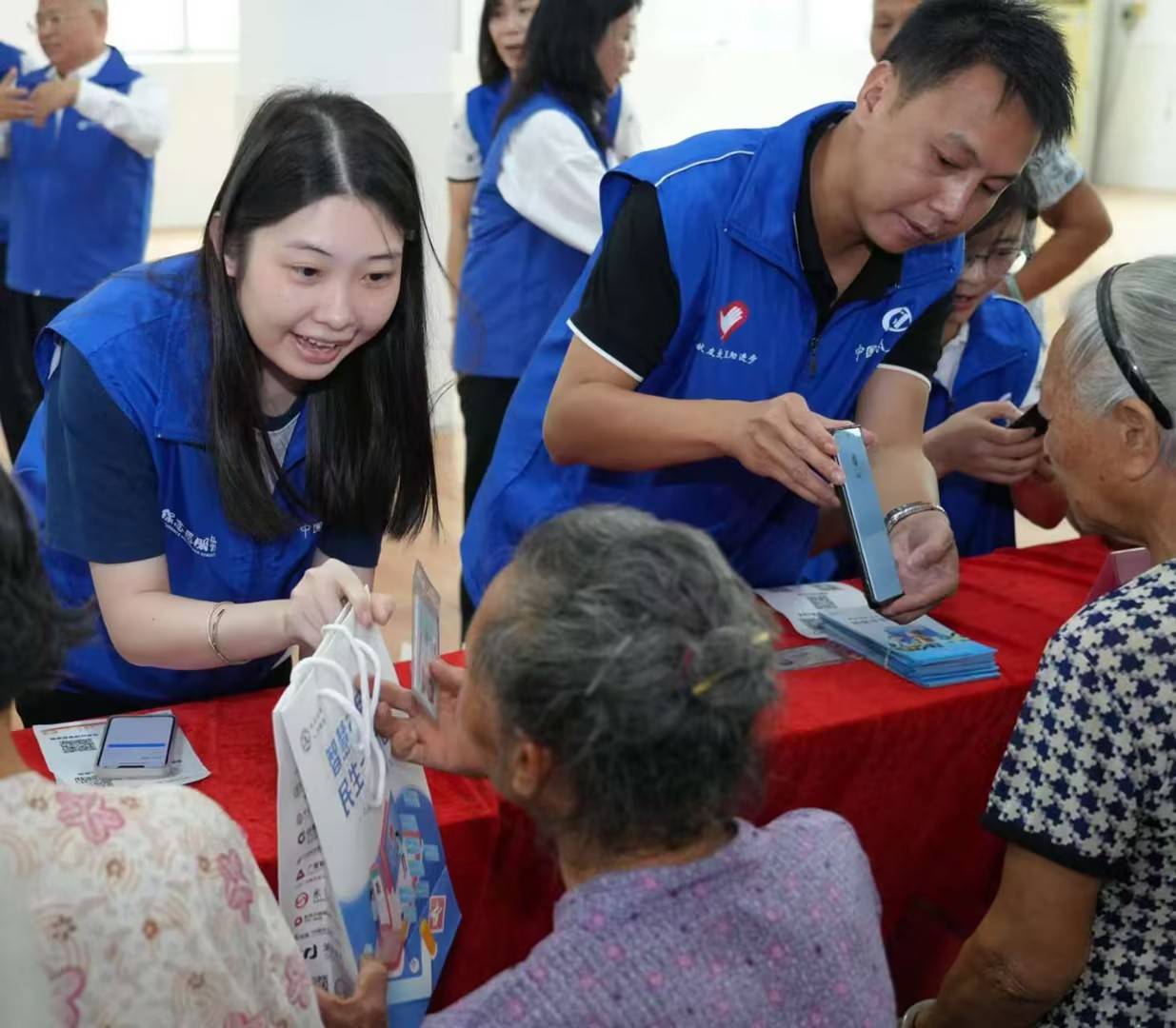 来自社保志愿服务东莞分队的志愿者们正在用手机耐心地为老人办理养老