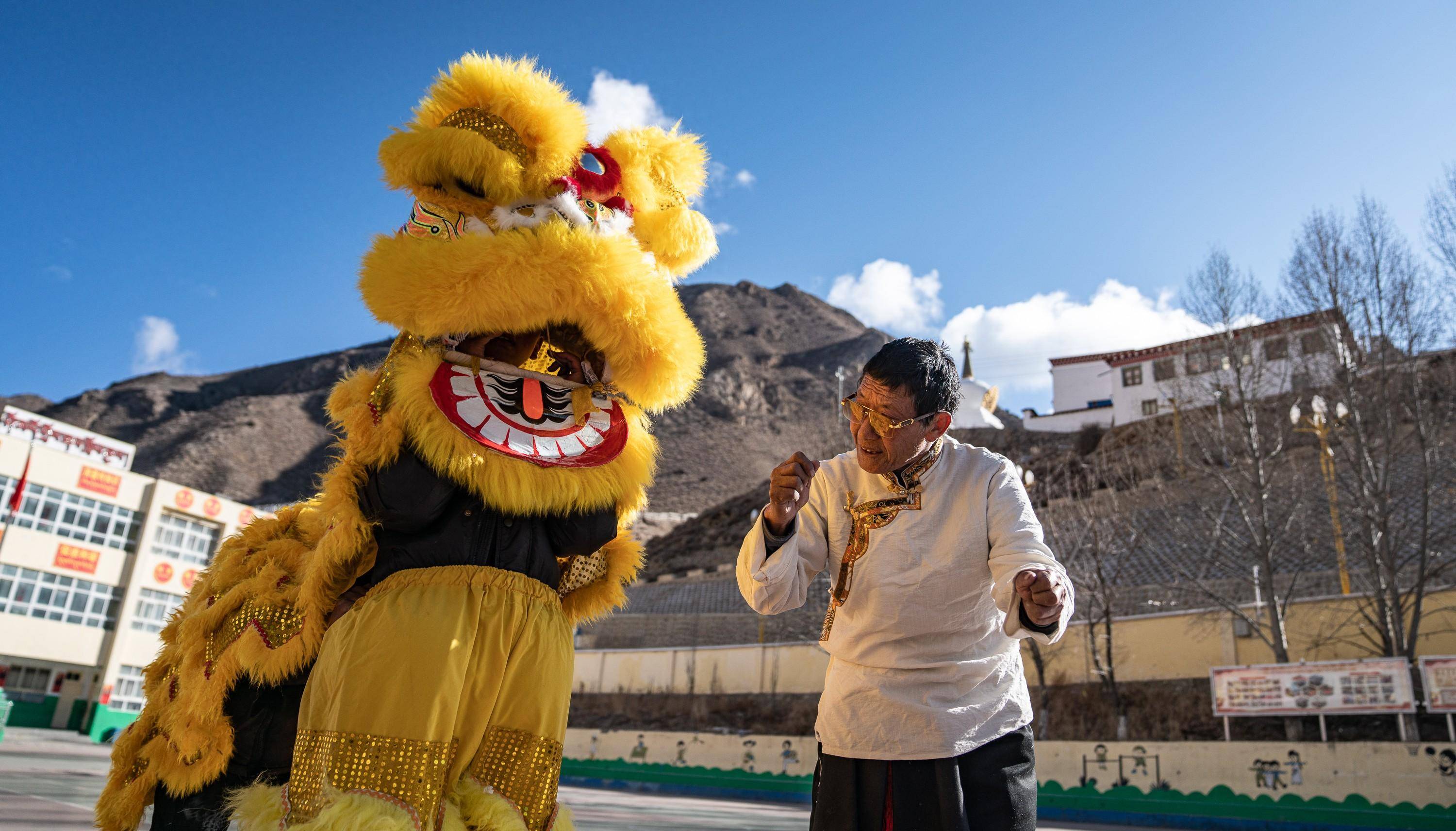 在西藏昌都市洛隆县硕督镇小学,邓巴阿尼(右)指导学生们跳狮子舞(1月