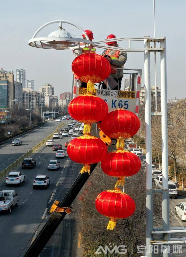 车上的工作人员将一串串喜庆的大红灯笼悬挂到文峰中路两侧的路灯杆上