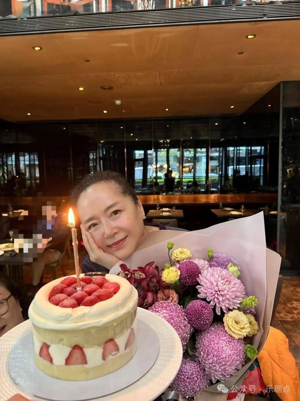 "照片见恬妞捧着一束鲜花,前面有一个生日蛋糕,似乎在餐厅与朋友庆生