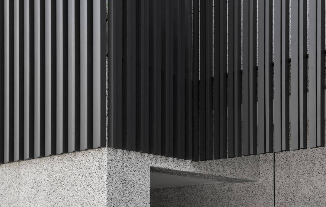 建筑物的外部採用方形水泥空心砖,抿石子和深灰色铝格栅,勾勒出一个长