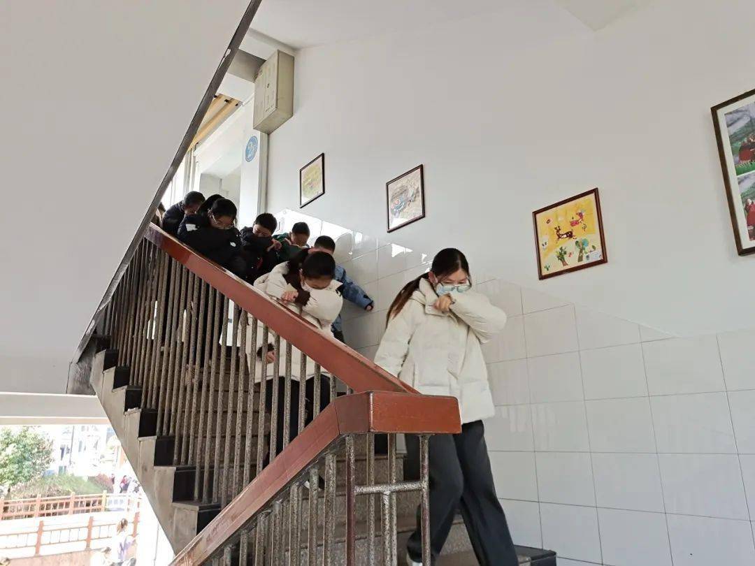 各班正副主任带领学生弯着腰,用手帕,毛巾,衣袖等捂住口鼻,沿着通道