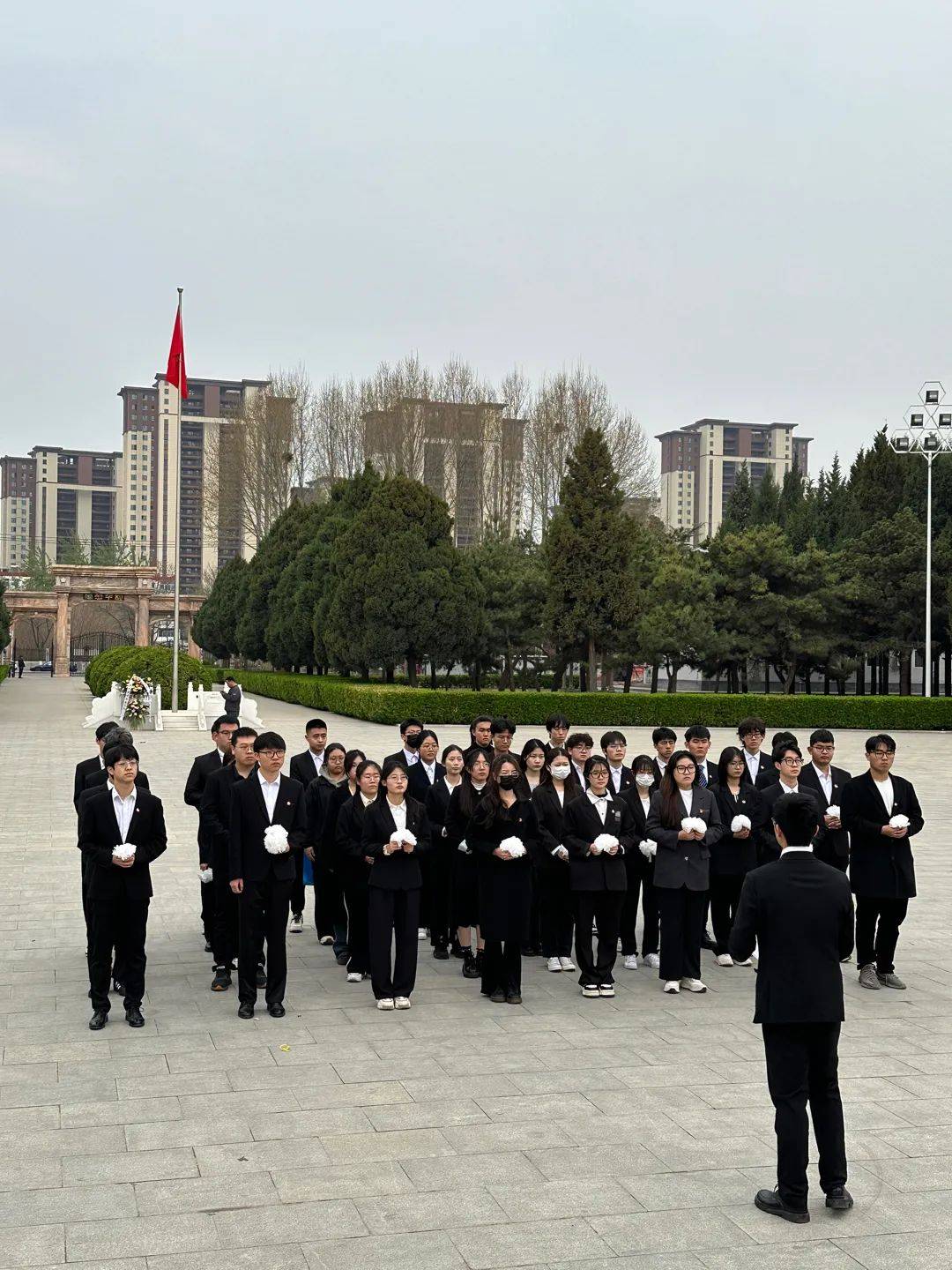在英烈亭前全体人员神情肃穆共同奏唱国歌向国旗敬礼瞻仰纪念碑并