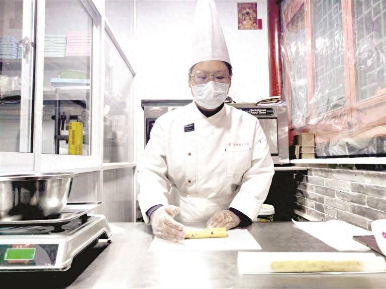 "90后""创客"赵丽君身着厨师服,头戴厨师帽,正忙碌着:烤制蛋糕胚子,修