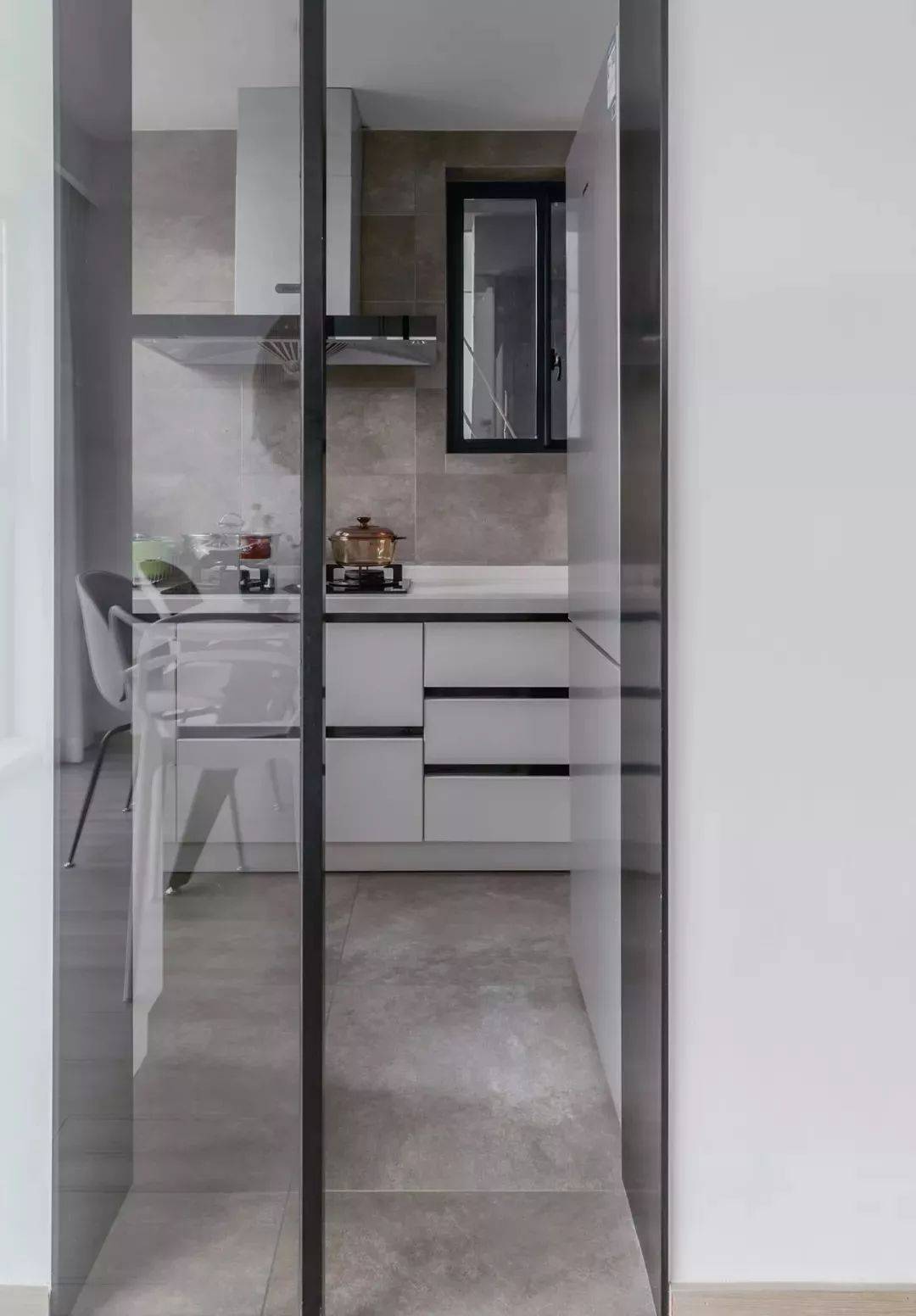 厨房内部铺贴了水泥质感的墙地砖,搭配白色橱柜,显得更加简洁,质朴.