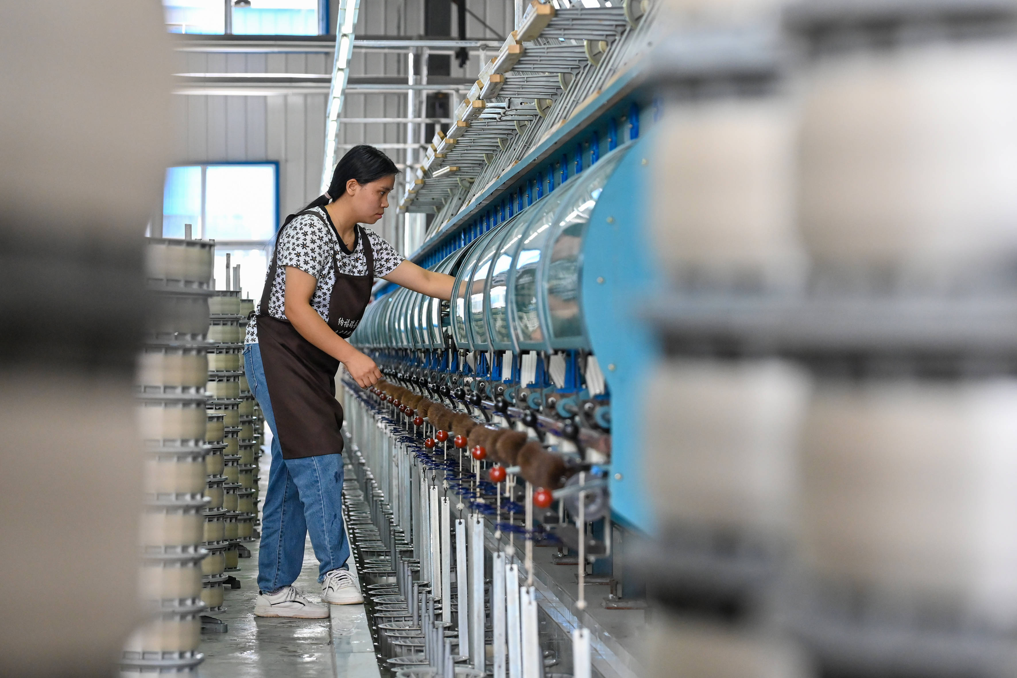 缫丝车间里机器轰鸣,两组自动缫丝生产线飞速运转,工人们在一排排机器