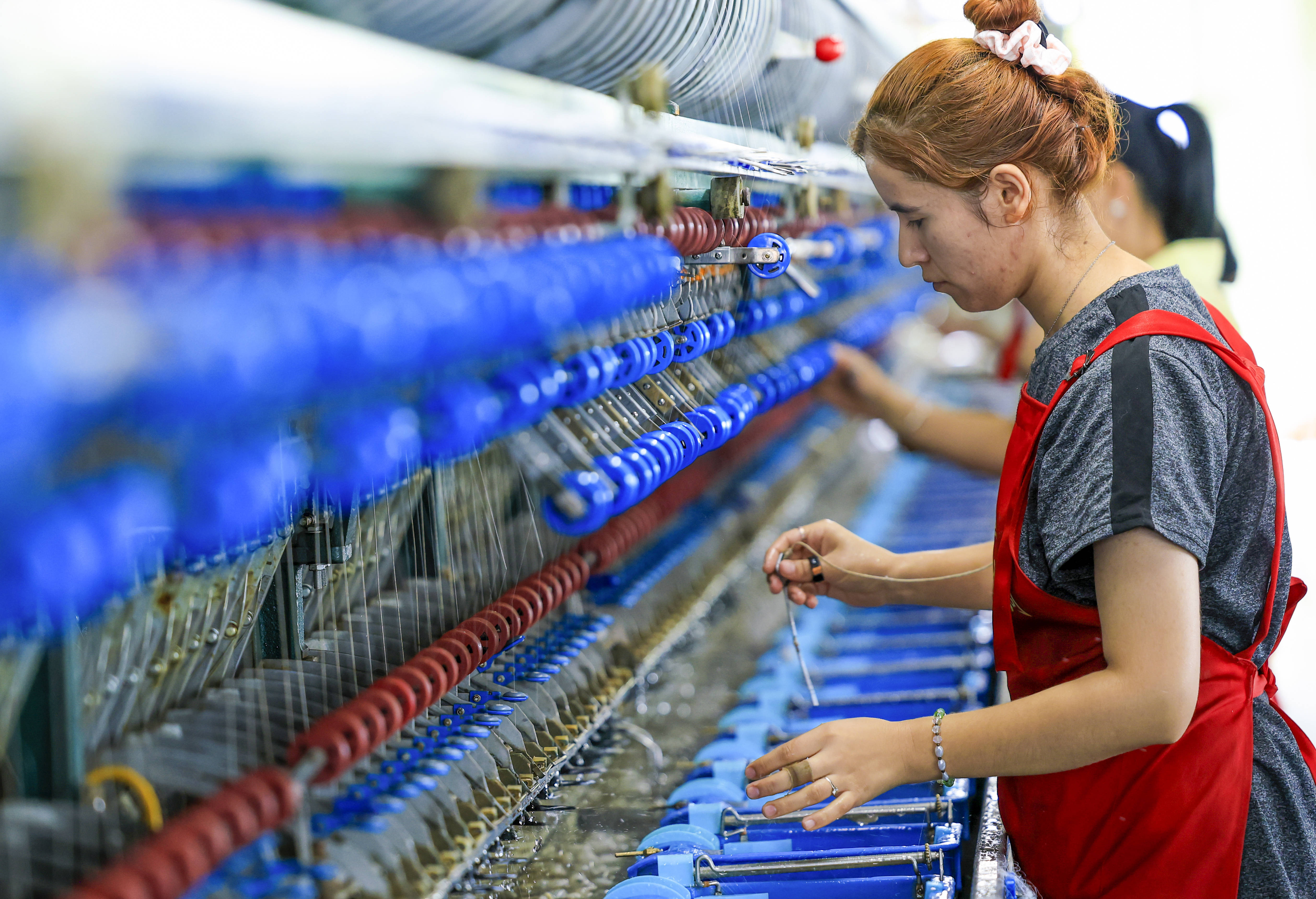 7月29日,工人在新疆丝锦丝绸纺织有限公司生产车间内的自动缫丝机上